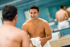 Handsome man looking in the mirror at the bathroom